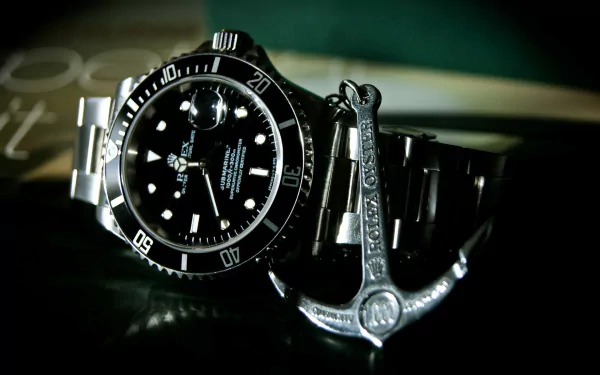HD desktop wallpaper featuring a close-up of a man-made Rolex watch with a detailed anchor charm beside it.