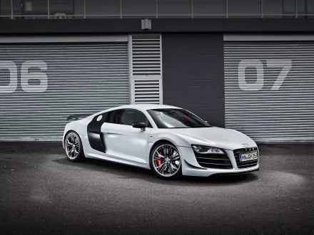 HD PC desktop wallpaper showcasing a sleek white Audi sports car parked in front of industrial garage doors numbered 06 and 07.