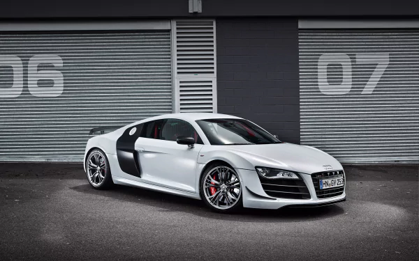 HD PC desktop wallpaper showcasing a sleek white Audi sports car parked in front of industrial garage doors numbered 06 and 07.