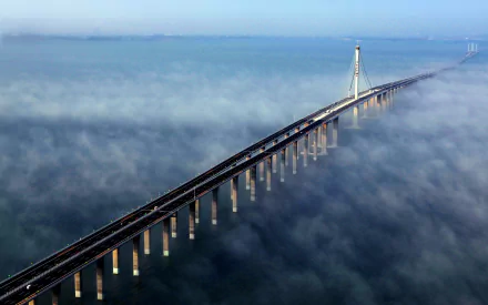 A stunning HD desktop wallpaper showcasing the Jiaozhou Bay Bridge stretching over a fog-covered sea.