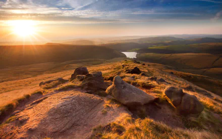 Sunset over a rocky landscape in England, showcasing rolling hills and a winding river, captured in HD for a nature-themed PC desktop wallpaper.