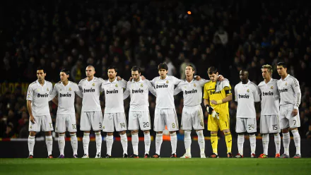Real Madrid C.F. team lined up on the field, wearing white uniforms, standing together before a match. This HD wallpaper and background captures the spirit and unity of the iconic sports club.