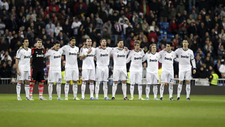 A lineup of Real Madrid C.F. players in their white uniforms, standing together on the field, celebrating a significant moment in sports. 4K Ultra HD desktop wallpaper.