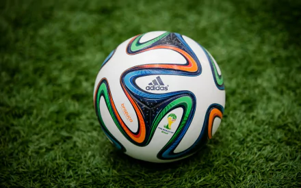 A vibrant Adidas soccer ball rests on green turf, symbolizing the FIFA World Cup Brazil 2014, serving as an energetic desktop wallpaper and background for sports enthusiasts.