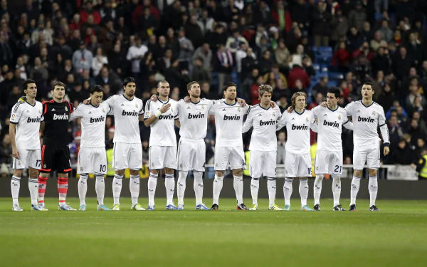 A lineup of Real Madrid C.F. players in their white uniforms, standing together on the field, celebrating a significant moment in sports. 4K Ultra HD desktop wallpaper.