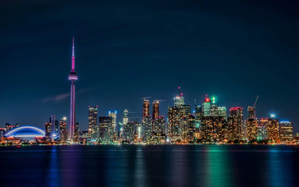 A stunning night view of Toronto's skyline, showcasing the CN Tower and vibrant city lights reflected in the water, capturing the man-made beauty of Ontario.
