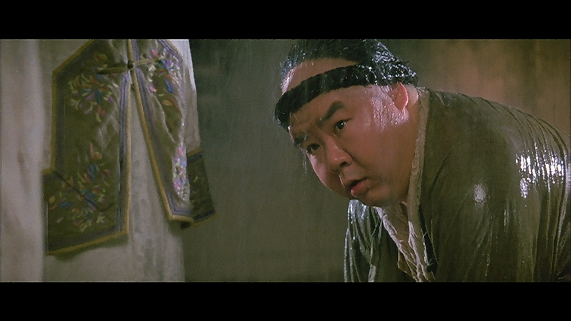 HD PC desktop wallpaper from the movie Once Upon a Time in China: a soaked, headband-wearing man leans forward in a dim, ornate interior.