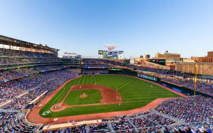 A panoramic view of Target Field in Minneapolis, Minnesota, bustling with fans, showcasing the vibrant atmosphere of a Minnesota Twins baseball game under a clear blue sky.
