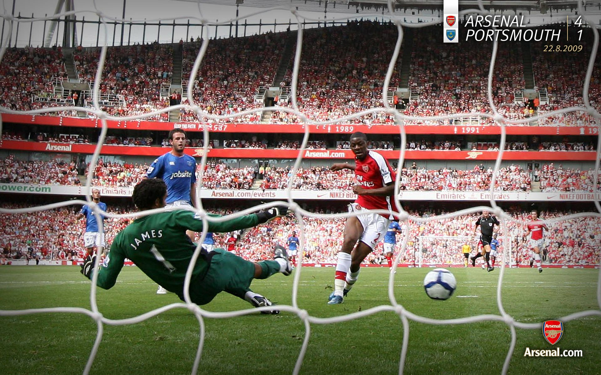 HD desktop wallpaper featuring an Arsenal F.C. match moment with players and goalkeeper in action at a packed stadium in this sports-themed background.
