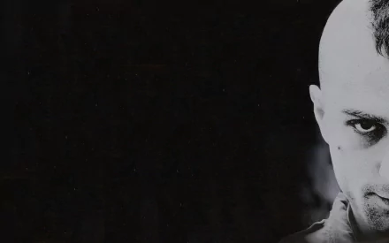 Black and white HD wallpaper featuring Robert De Niro in a dramatic close-up from the movie Taxi Driver, capturing his intense gaze against a dark background.