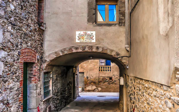 HD desktop wallpaper of a narrow man-made alley with stone and plaster walls, an arched passage, and a small window above, capturing rustic architectural details.