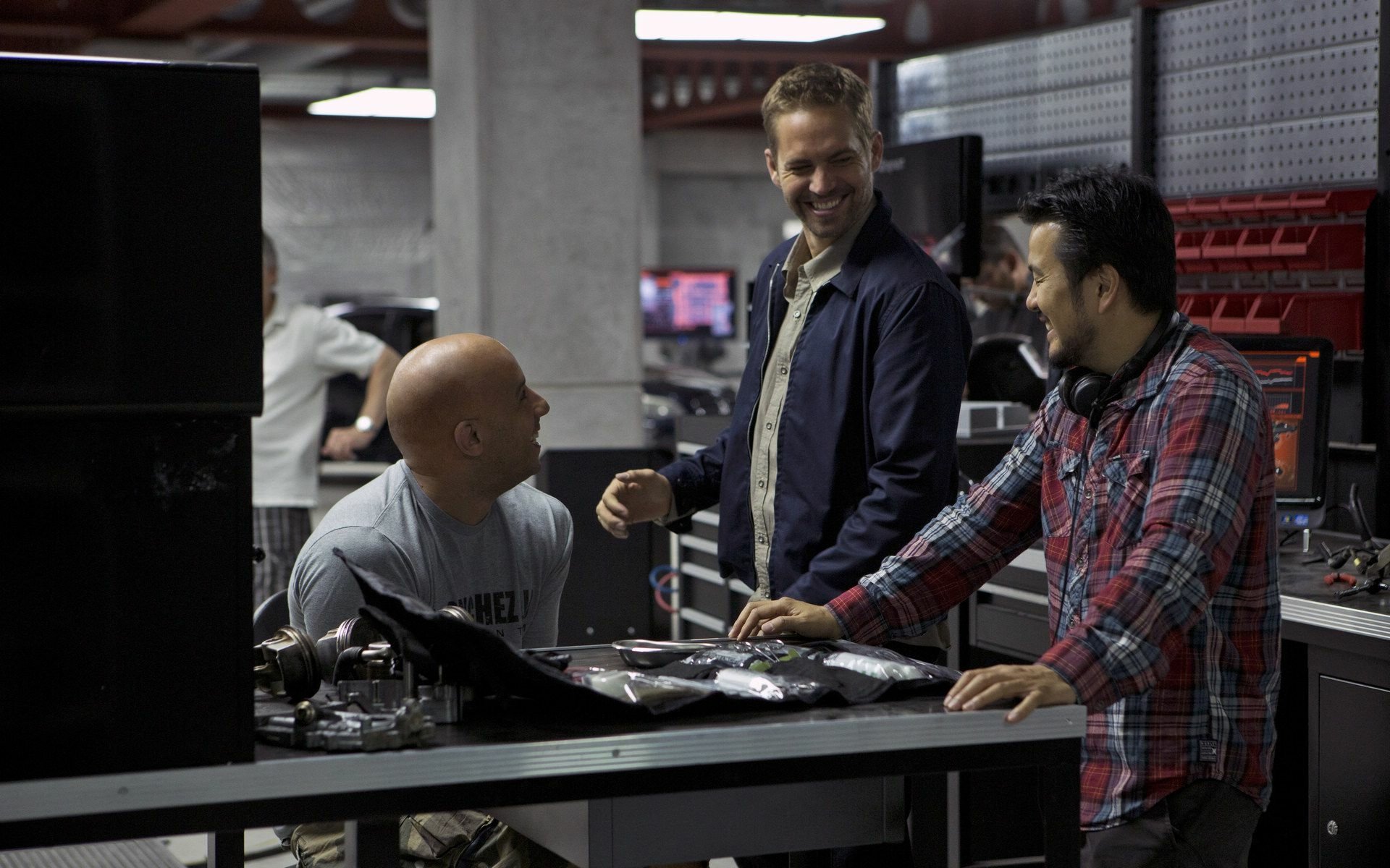 A behind-the-scenes moment from *Fast & Furious 6*, featuring Vin Diesel as Dominic Toretto and Paul Walker as Brian O'Conner, captured while working in a tech-filled setting.