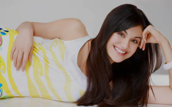 A vibrant HD desktop wallpaper featuring celebrity Adah Sharma smiling while lying down, showcasing her long hair and a playful outfit with colorful designs.