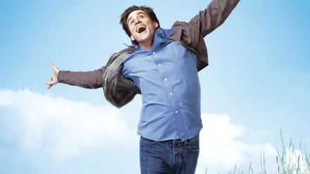 HD desktop wallpaper featuring Jim Carrey joyfully jumping, from the movie Yes Man, against a bright blue sky background.