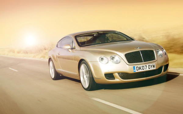 HD desktop wallpaper featuring a Bentley Continental GT Speed driving on a sunlit road, showcasing its sleek design and luxury performance.