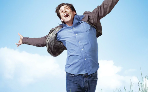 HD desktop wallpaper featuring Jim Carrey joyfully jumping, from the movie Yes Man, against a bright blue sky background.
