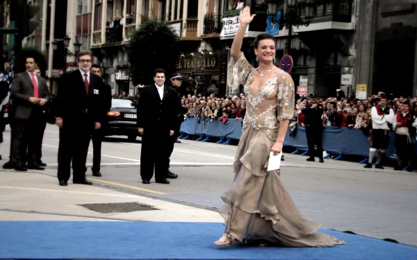 Yelena Isinbayeva waves to the crowd on a city street, dressed elegantly at a public event, captured in a high-definition sports-themed desktop wallpaper.
