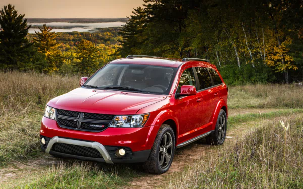 HD PC desktop wallpaper background: red Dodge Journey SUV parked on a grassy trail with autumn trees and rolling hills.