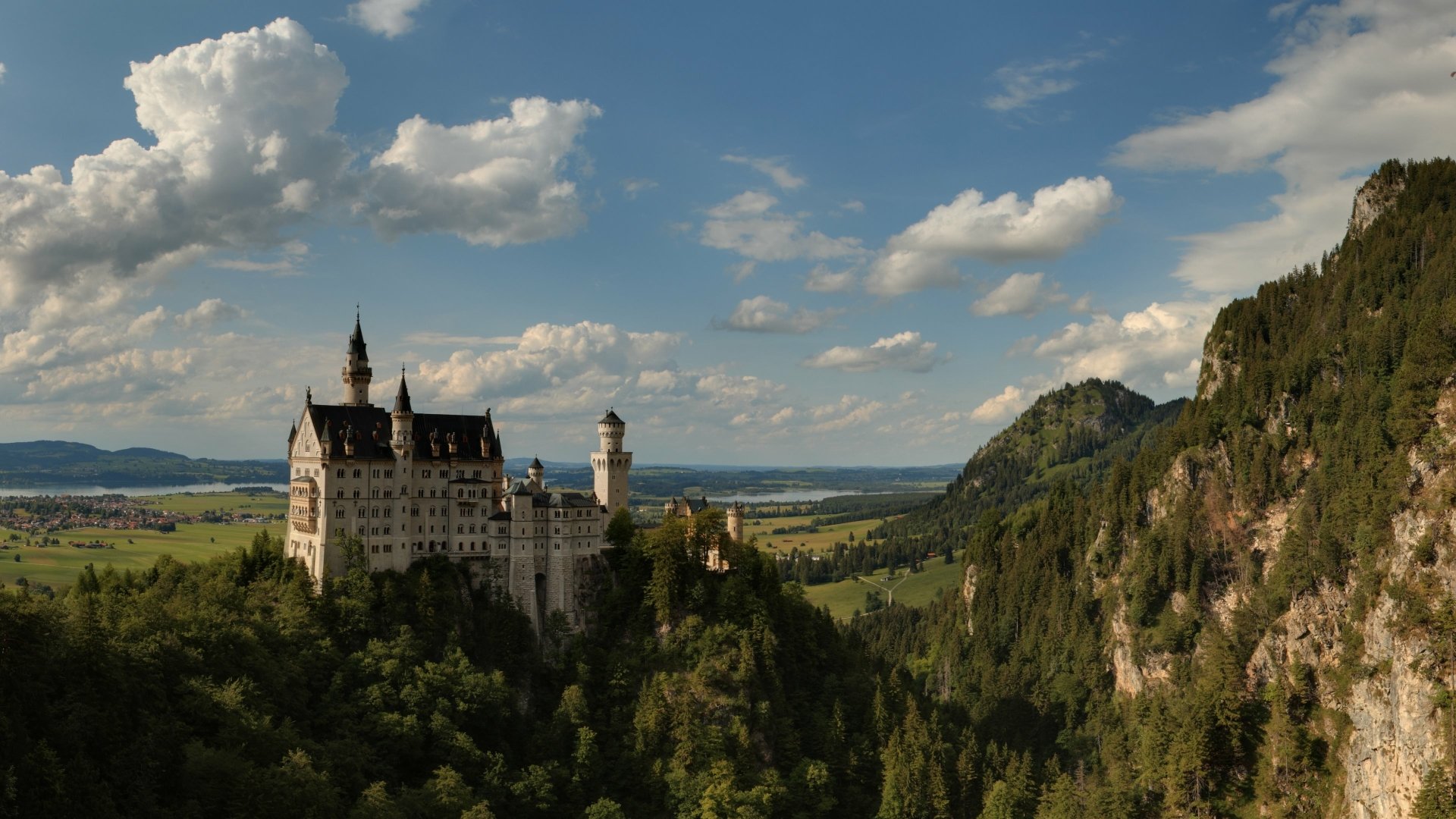 Neuschwanstein Castle, a majestic man-made structure, set against a scenic mountainous landscape under a partly cloudy sky, captured in stunning 4K Ultra HD.