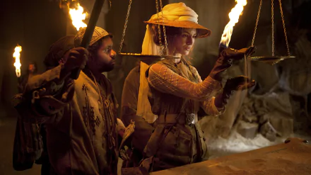Scene from the movie The Extraordinary Adventures of Adèle Blanc-Sec showing characters holding torches in a dim, fiery environment, featured as a 4K Ultra HD PC wallpaper.
