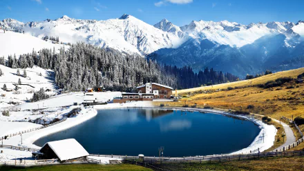 4K Ultra HD photography of a serene mountain lake surrounded by snow-covered peaks, evergreen trees, and a rustic lodge under a clear blue sky.