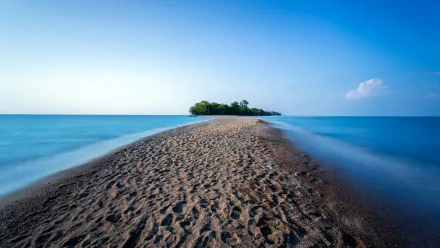 A serene landscape showcasing a sandy path leading to a lush island, surrounded by calm blue waters under a clear sky. 4K Ultra HD desktop wallpaper for nature lovers.