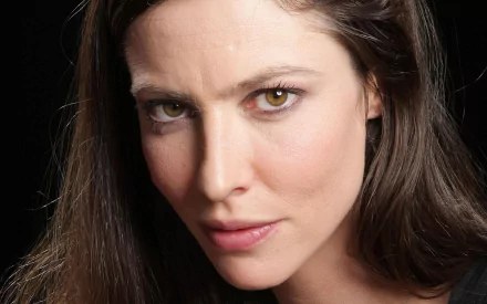 HD PC desktop wallpaper close-up of a French actress — a woman with long dark hair, hazel eyes and an intense, focused expression against a dark background.