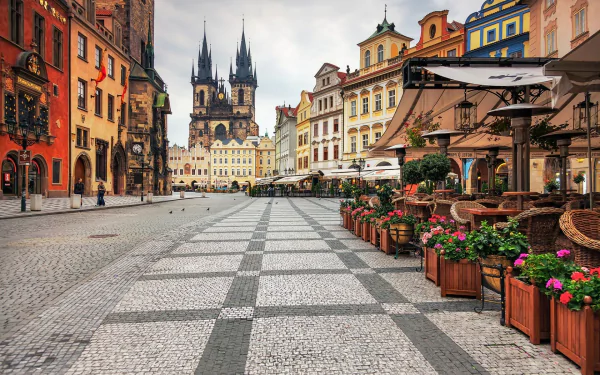 HD desktop wallpaper of a picturesque cobblestone square in Prague, featuring colorful buildings and the iconic Gothic spires of Tyn Church.