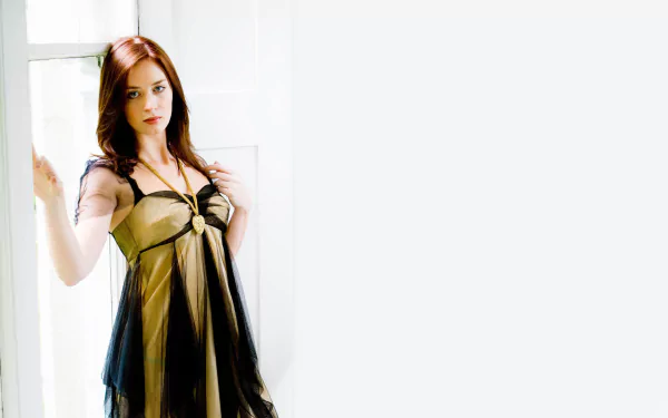 HD desktop wallpaper featuring English actress Emily Blunt posing in a sheer black dress against a bright, minimalistic background.