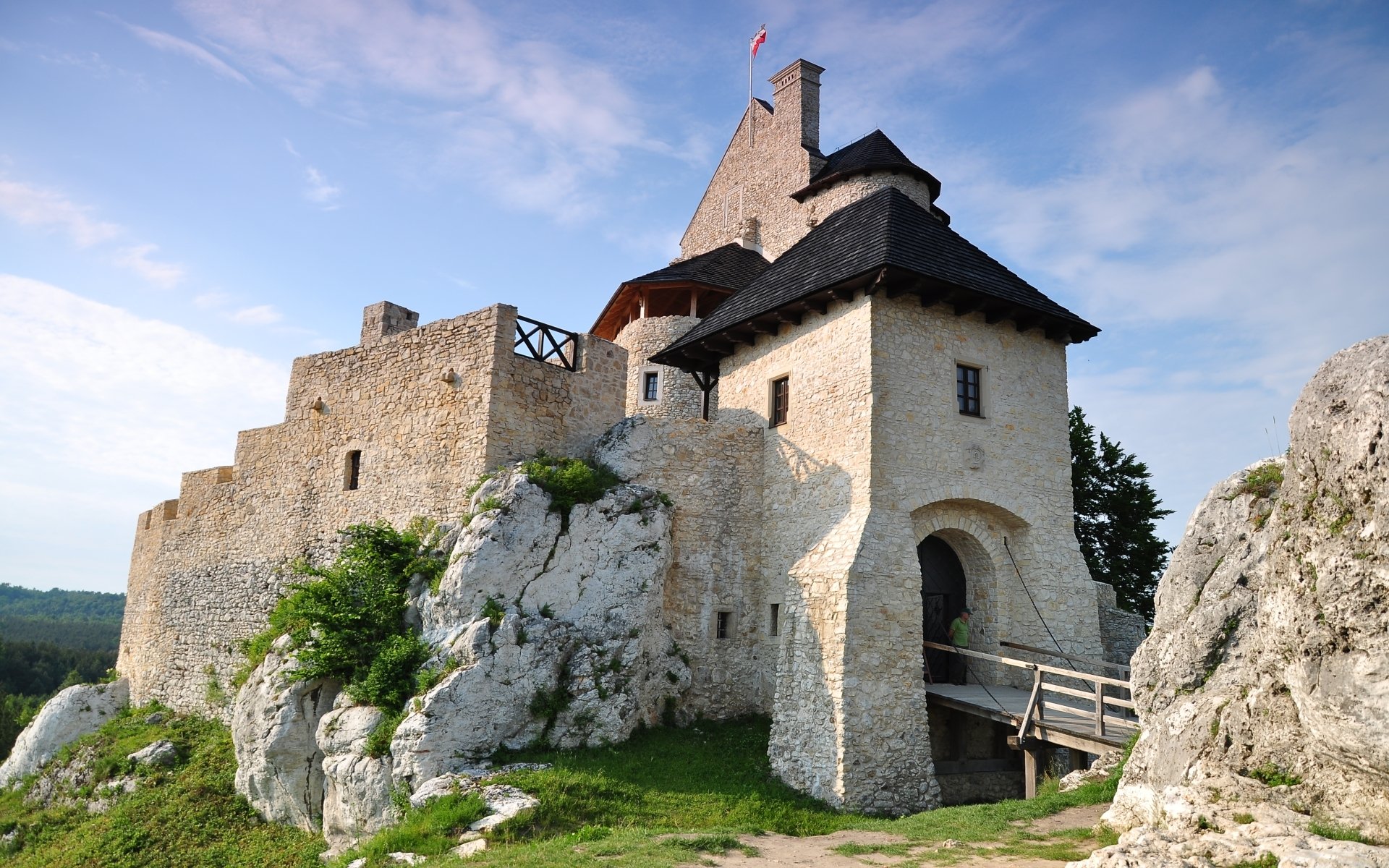 HD PC desktop wallpaper of man-made Bobolice Castle on a rocky hill, with stone walls and a wooden bridge beneath a clear blue sky.