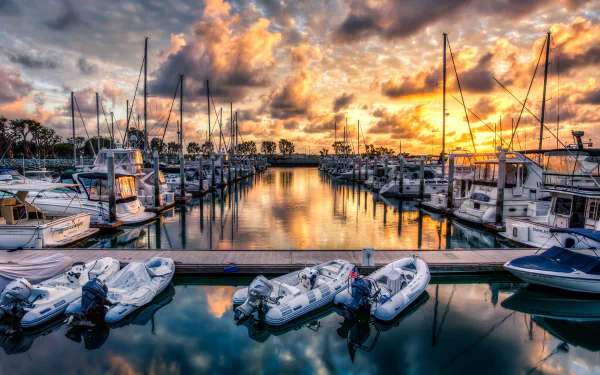A serene harbor scene at sunset, featuring boats docked in calm waters, reflecting vibrant clouds and a tranquil atmosphere. A stunning 4K Ultra HD desktop wallpaper.
