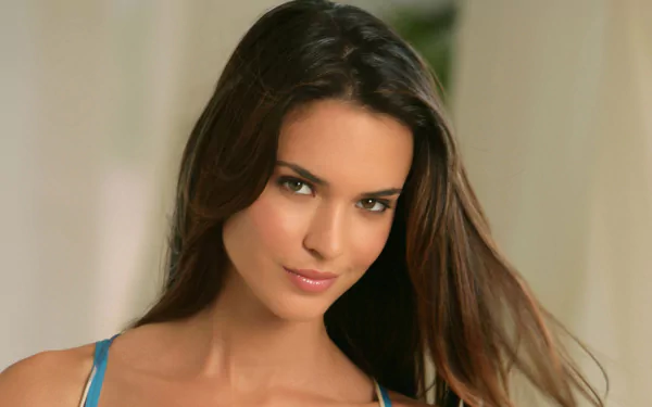 A stunning HD desktop wallpaper featuring American actress Odette Annable, showcasing her captivating smile and long, flowing hair in a softly lit setting.