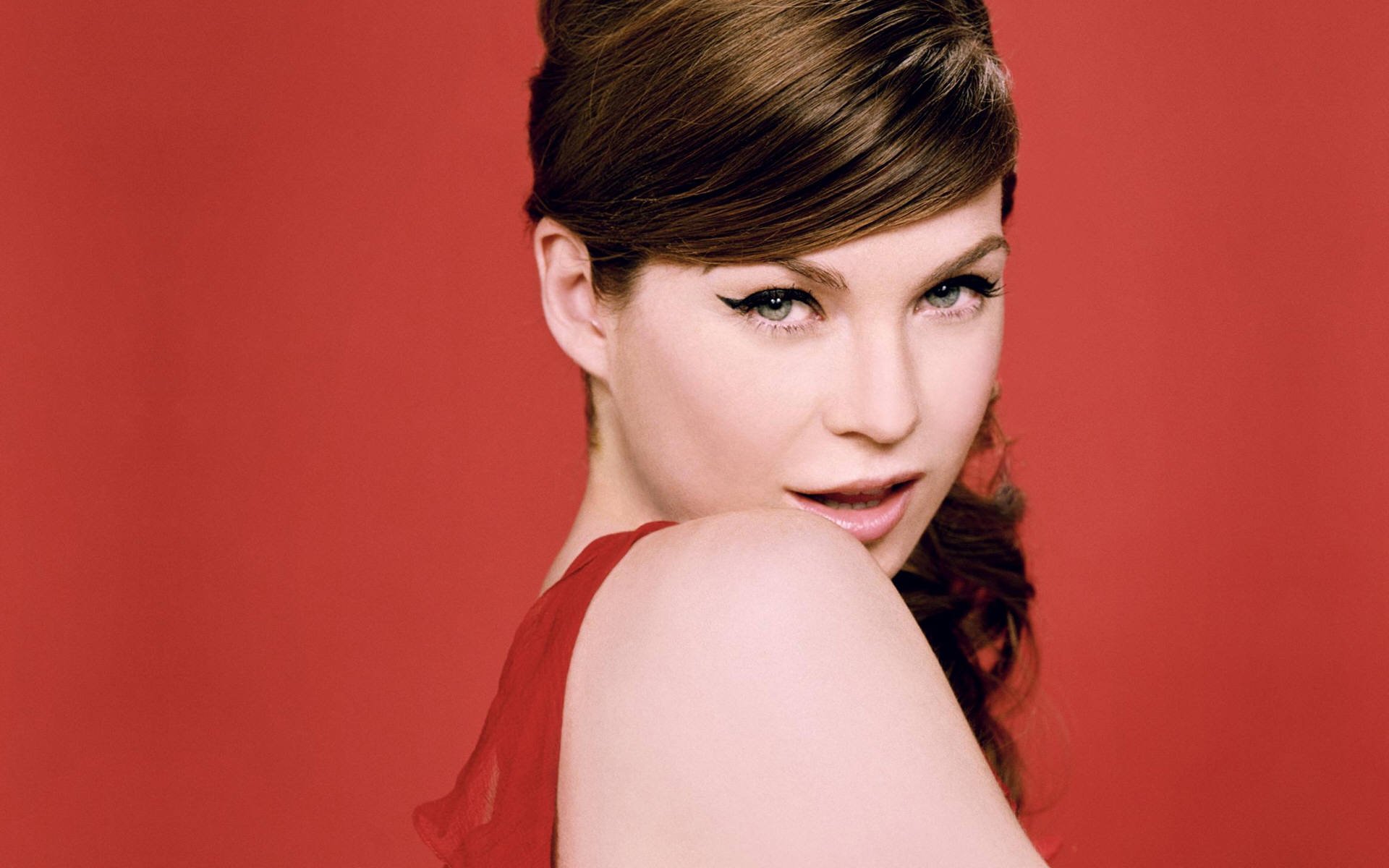 HD desktop wallpaper of an American actress and celebrity in a red dress, posing over a red backdrop.