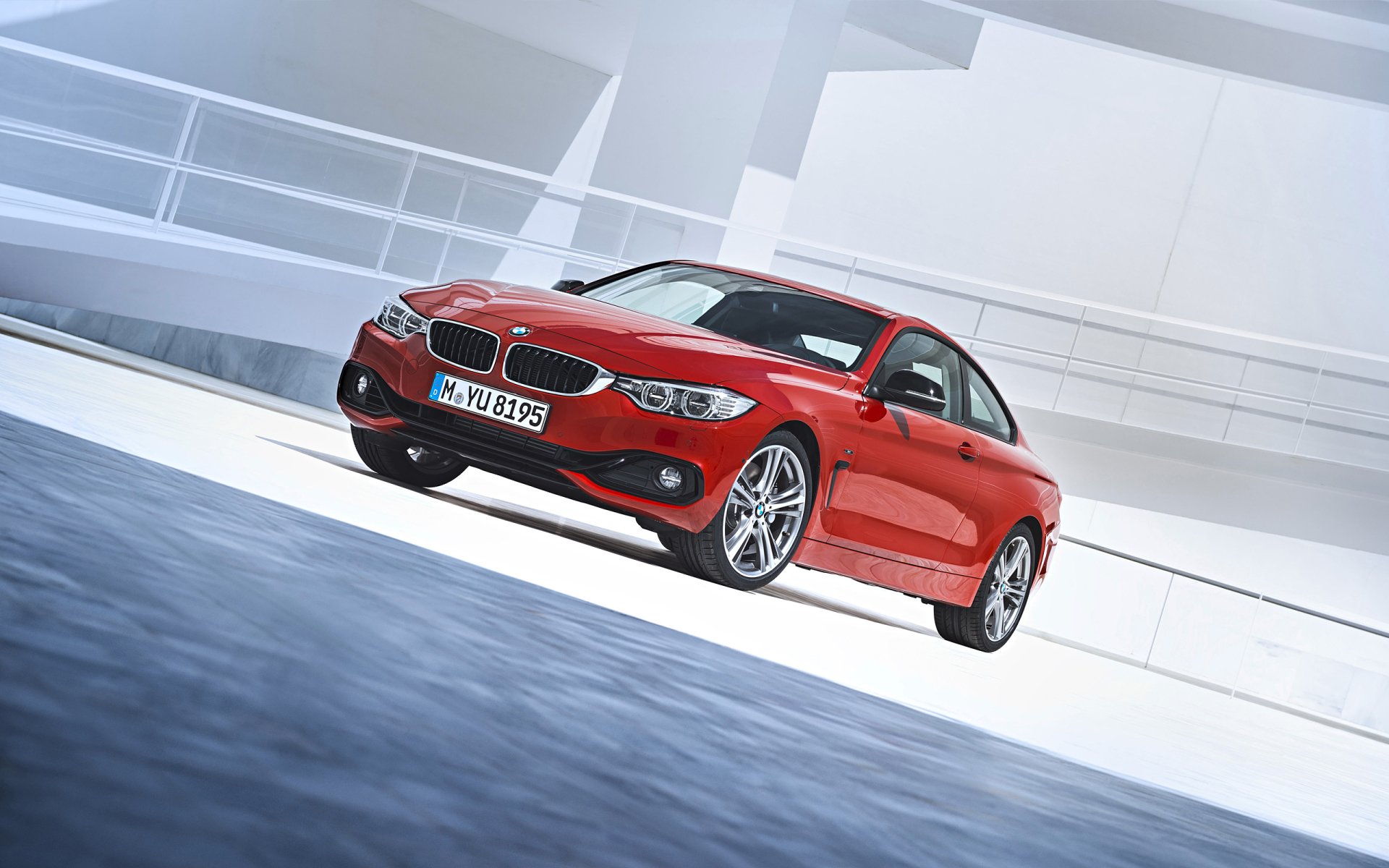 Red BMW 4 Series Coupe against a modern architectural backdrop — 2K Quad HD PC desktop wallpaper, dynamic low-angle view of the vehicle.
