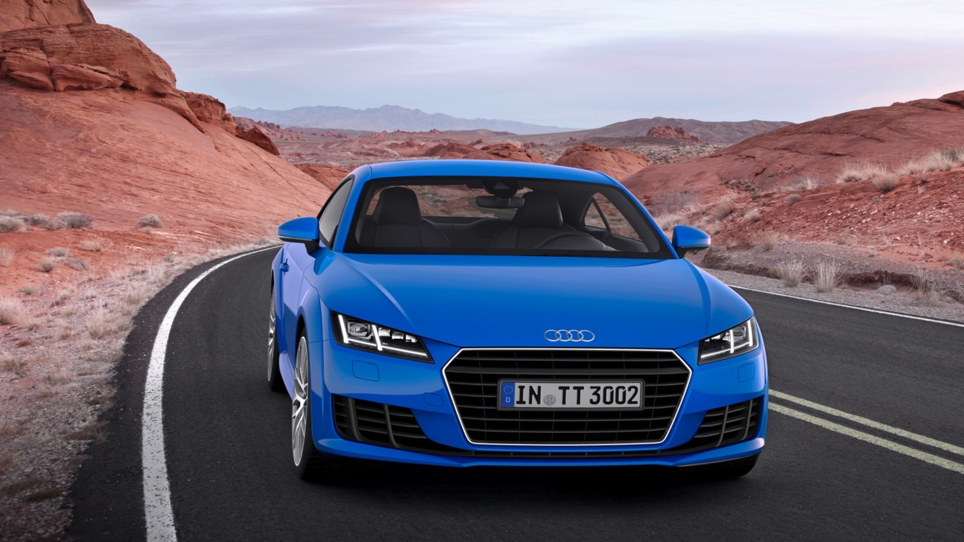 Blue Audi TT sports car on a winding desert road with red rock formations, HD PC desktop wallpaper background.