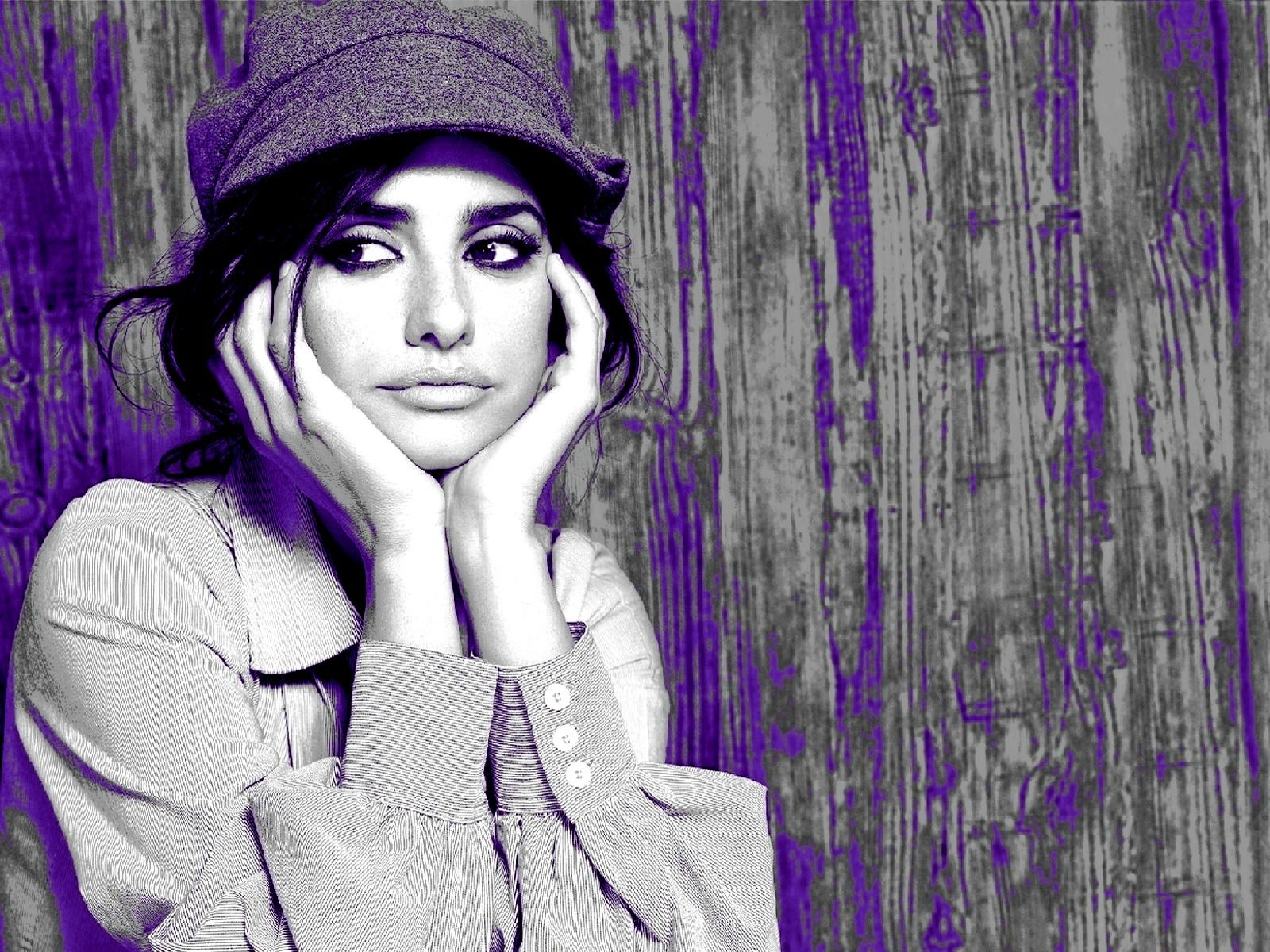 HD PC desktop wallpaper featuring a stylized black-and-white portrait of celebrity Penelope Cruz wearing a hat against a textured purple and wooden background.