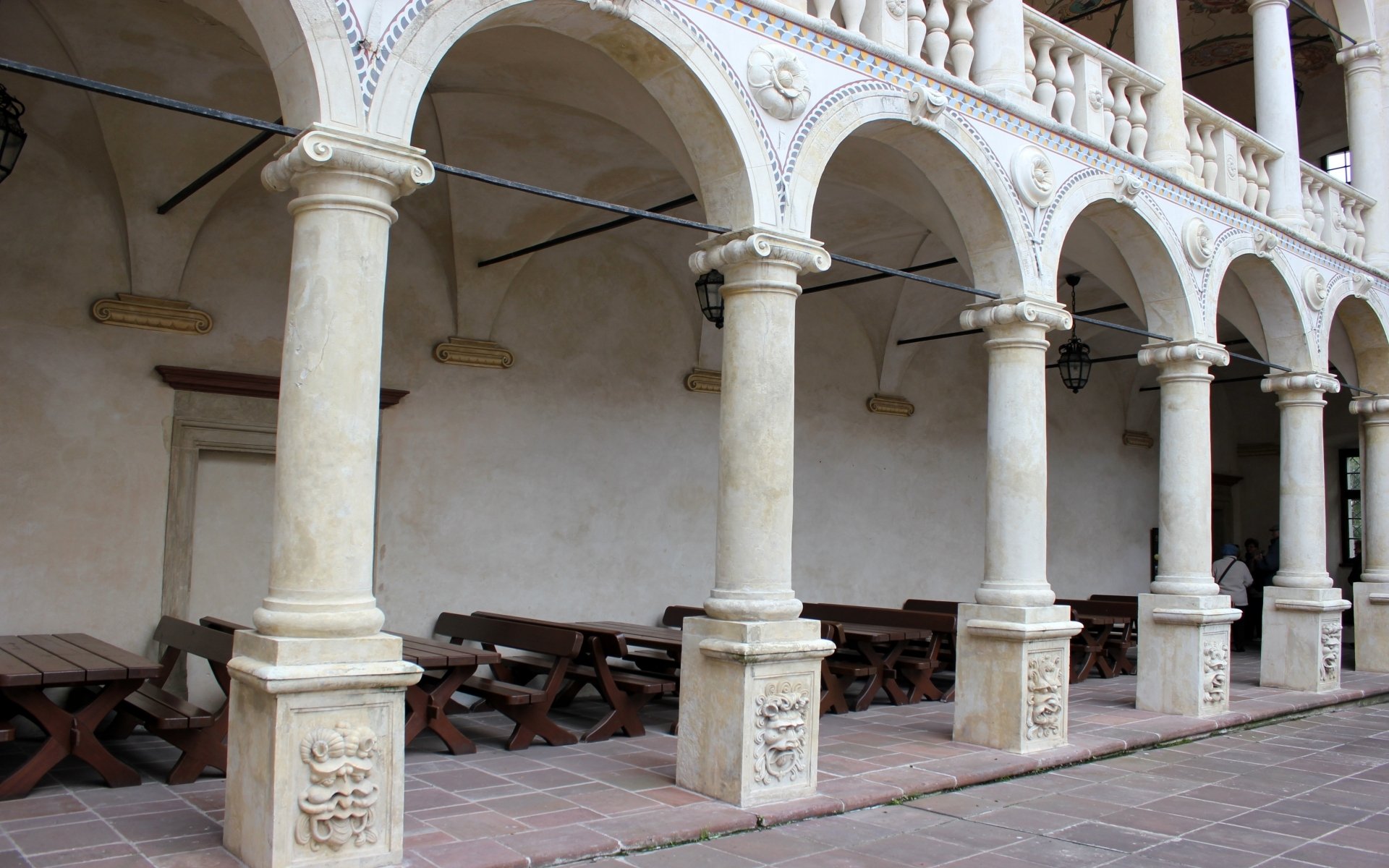 Man-made pale stone colonnade with ornate columns and arches at Baranów Sandomierski Castle — HD PC desktop wallpaper/background.