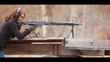 A woman in protective gear aiming a machine gun at a target, showcasing precision and focus. This HD desktop wallpaper captures action and intensity in a striking outdoor setting.