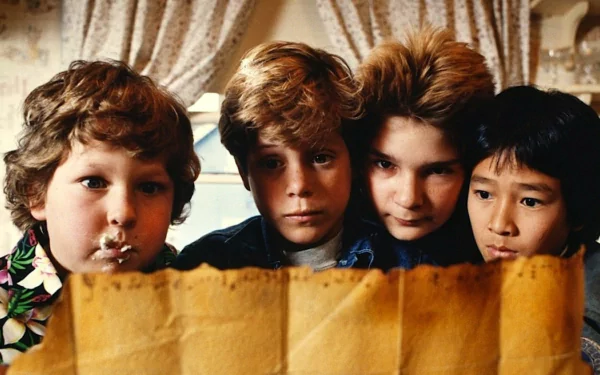 HD PC desktop wallpaper featuring a scene from the movie The Goonies with four kids intently examining an old treasure map.