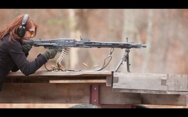 A woman in protective gear aiming a machine gun at a target, showcasing precision and focus. This HD desktop wallpaper captures action and intensity in a striking outdoor setting.