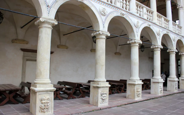 Man-made pale stone colonnade with ornate columns and arches at Baranów Sandomierski Castle — HD PC desktop wallpaper/background.