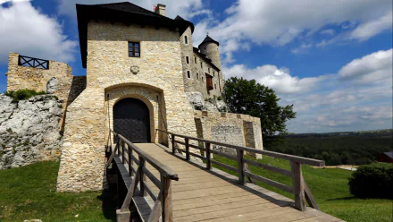 HD PC desktop wallpaper and background of Bobolice Castle, a man-made medieval stone fortress with a wooden bridge and arched gate beneath a blue sky.