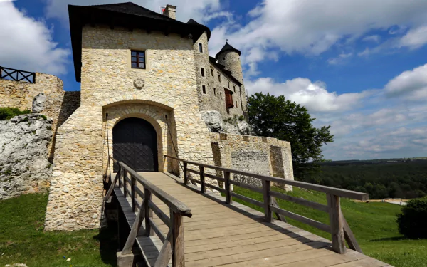 HD PC desktop wallpaper and background of Bobolice Castle, a man-made medieval stone fortress with a wooden bridge and arched gate beneath a blue sky.