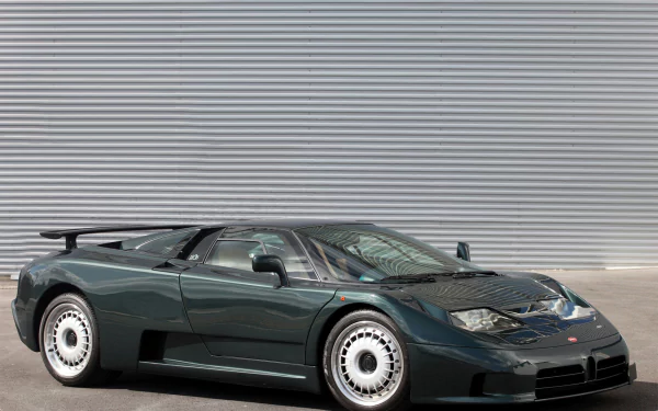 HD PC desktop wallpaper: dark green Bugatti EB110 GT parked low in front of a corrugated metal wall, three-quarter front view showcasing its aerodynamic lines and white multi-hole wheels.