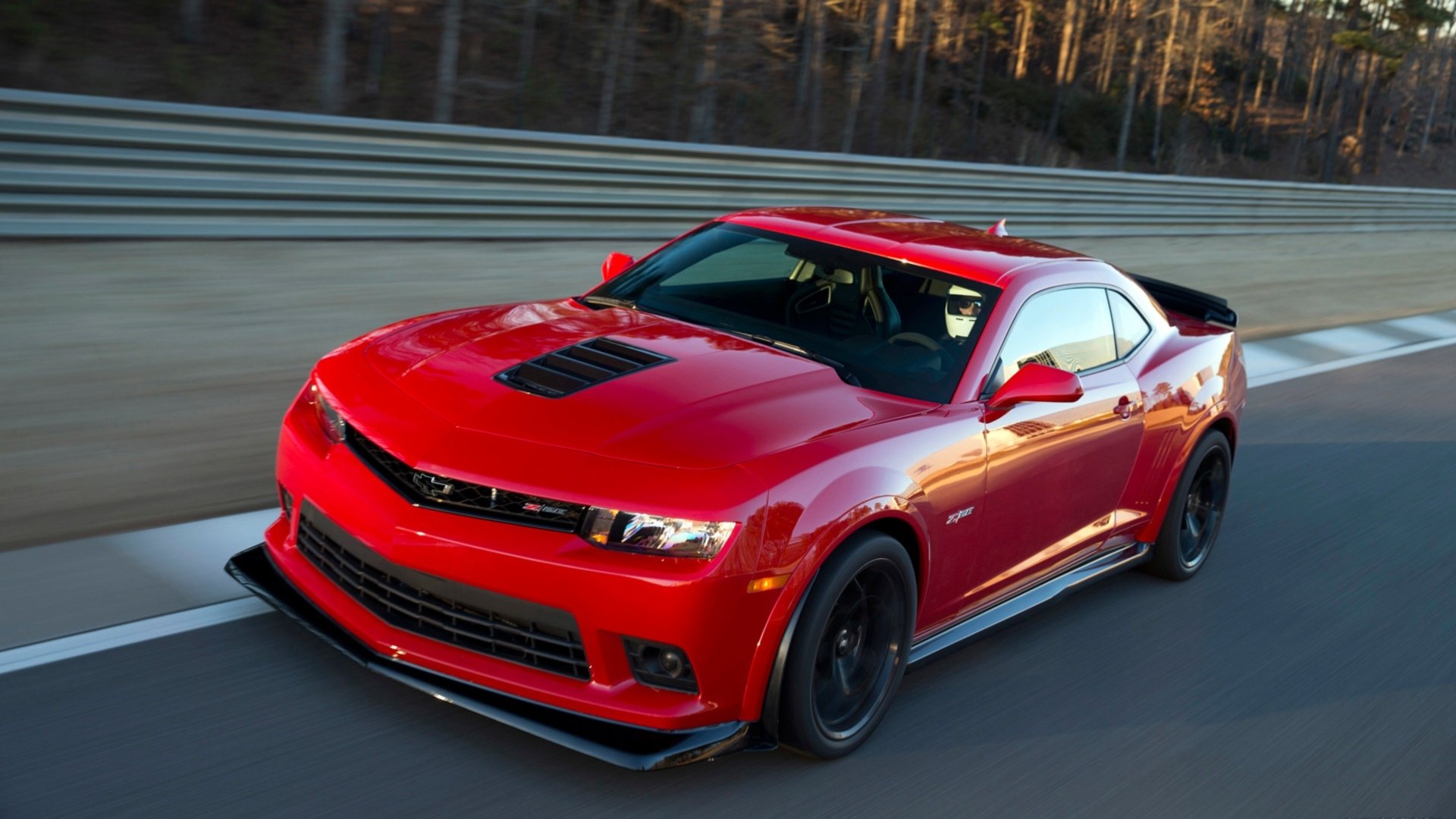 A red Chevrolet Camaro Z28 speeding on a racetrack, captured in a high-definition desktop wallpaper background.