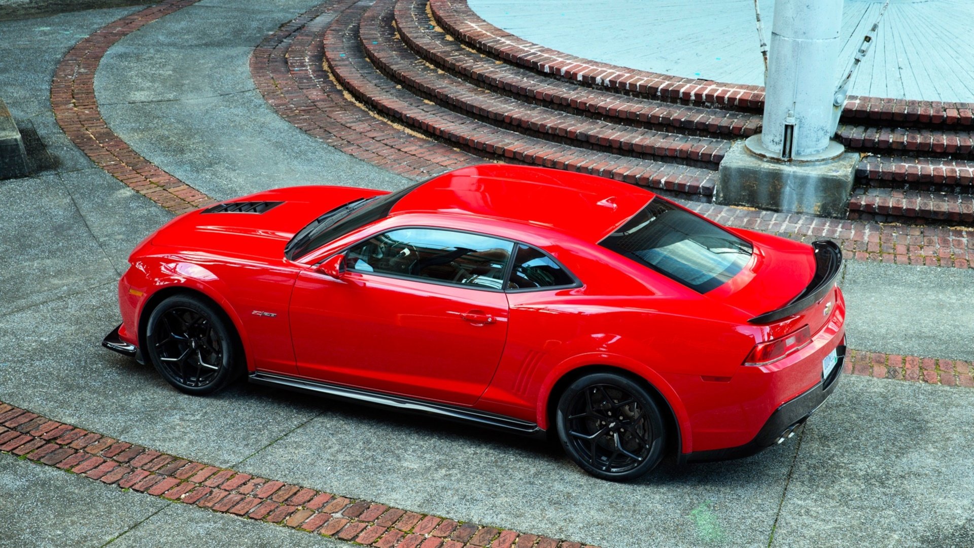 A vibrant red Chevrolet Camaro Z28 parked on a brick and concrete surface, showcased in an HD PC desktop wallpaper and background.