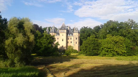 HD PC desktop wallpaper featuring the man-made Goluchów Castle surrounded by lush greenery under a partly cloudy sky.