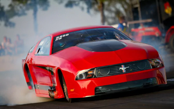 HD PC desktop wallpaper featuring a red Ford Mustang in action, drifting with smoke trailing behind the vehicle.