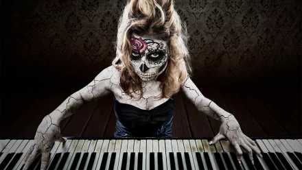 Artistic HD PC desktop wallpaper featuring a woman with detailed sugar skull face paint and cracked body art playing piano against a dark, textured background.