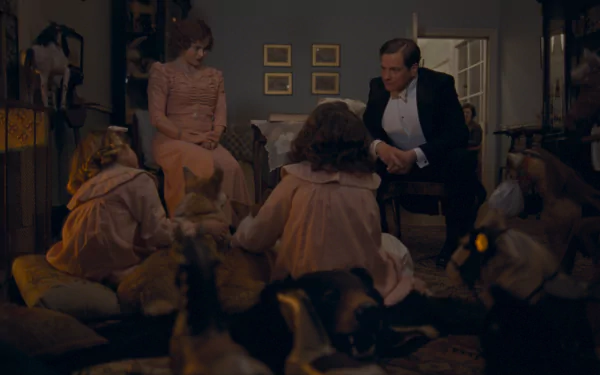 Still from the film The King's Speech: the royal couple sit in a dim parlor while their young daughters play on the floor amid scattered toys.